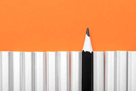 Single black pencil between a group of white pencils. Black people racism concept image with crayons. Sharp black pencil and other white pencils unsharpの写真素材