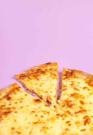 Sliced cheese pizza with mozzarella, close-up, isolated on a purple background with copy space. Slice of pizza with melted cheese. Homemade fast food.の写真素材