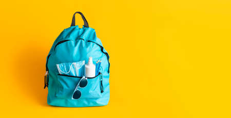 Back to school concept during Corona pandemic. Schoolbag with medical masks, disinfectant and...