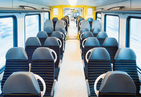 Passenger train interior with empty seats on two rows, in motion, in bright light. Train travel in Germany. Modern public transportation. No travelersの写真素材