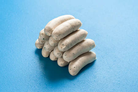 Pile of bavarian white sausage isolated on a blue background. Traditional german veal sausages stacked in a pyramidal shape. Home-cooked food.の写真素材