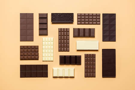 Chocolate bar assortment isolated on a beige background. Top view of fine chocolate collection, dark, milk, and white. Assorted baking chocolate.の写真素材