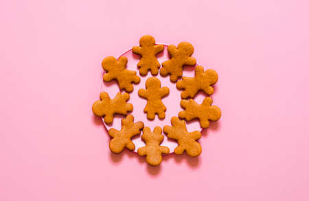 Gingerbread cookies, girl shaped, on a pink plate, isolated on pink background. Flat lay with plate of Christmas cookies. Homemade gingerbread dessertの写真素材