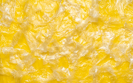 Above view with a multitude of single-use bags on a yellow background. Full-frame background with...
