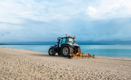 Morning beach scenery with tractor cleaning sand, at Baltic Sea, on Rugen Island, Germany. Getting beach ready for summer vacation. European travel.の写真素材