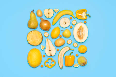 Variety of yellow only vegetables and fruits isolated on a blue background. Flat lay with sliced vegetables and fruits on a colored tableの写真素材