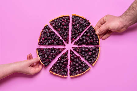 Hands grabbing slices of blueberries pie, above view minimalist. Homemade pie isolated on a purple...