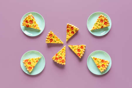 Above view with slices of quiche on a purple background. Homemade quiche sliced in equal portions...