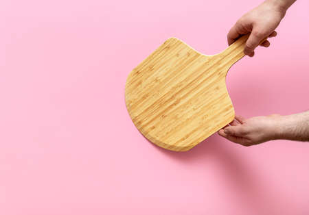Top view with a man's hand holding a pizza oven board. Empty wooden board minimalist on a...
