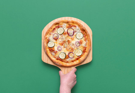 Delicious pizza with gorgonzola, zucchini and red onion rings. Homemade vegetarian pizza on a wooden board.の写真素材