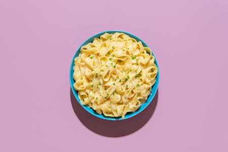 Top view with a pasta alfredo dish minimalist on a purple-colored table. Delicious fettuccine pasta with parmesan and butter, Italian recipe.の写真素材