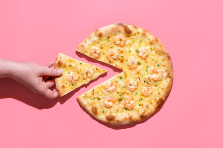 Woman's hand takes a slice of pizza, minimalist on a pink table. Delicious homemade pizza with...