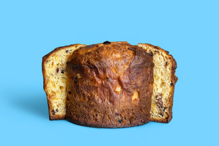 Homemade panettone with sourdough, raisins, chocolate and orange peel. Delicious panettone cake minimalist on a blue backgroundの写真素材