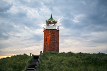 Landscape in the evening on the Sylt island in North Sea, Germany, with a red bricks lighthouse on the marram grass hillsの写真素材