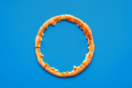 Above view with only the crust from a pizza, minimalist on a blue background. Pizza leftovers...