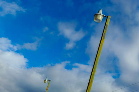 Lamp post. Street lamp. Electric post and a blue sky behind, with space for text. Background.