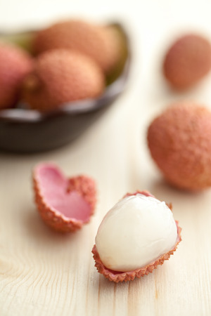 Lychees opened on a light wood tableの写真素材