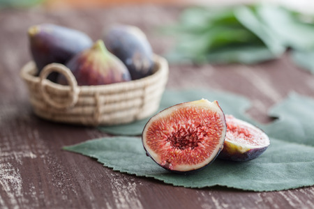 Figs of the season on a wooden table with fig leavesの写真素材
