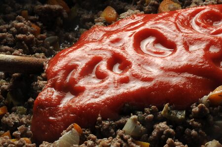 Adding tomato puree to minced meatの写真素材