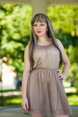Portrait of a beautiful young woman in a smart dress in a long brown-haired wigの写真素材