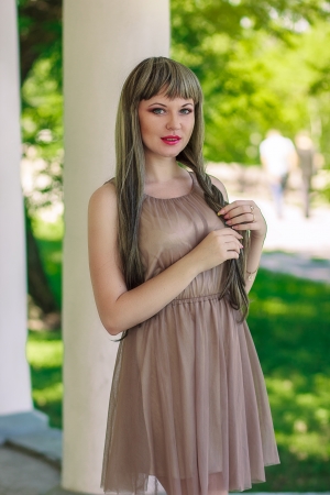Portrait of a beautiful young woman in a smart dress in a long brown-haired wigの写真素材