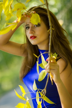 Portrait of very beautiful young brunette woman in a blue dress in an autumn natureの写真素材