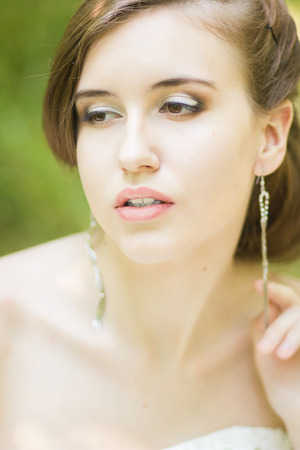 Portrait of a beautiful young bride in nature  Young woman holding a small bouquet of white roses in their handsの写真素材