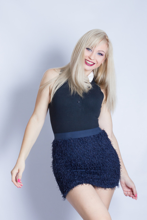 Portrait of a beautiful young blond woman in studio on a white background. Girl posing in blue skirt and black blouse
の写真素材