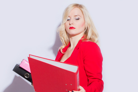 Portrait of a beautiful young blonde woman in a red business suit. The girl holds a folder for documents
の写真素材