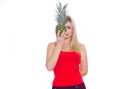 Sexy blonde with bright make-up, covers one half of her face with pineapple. Isolateの写真素材