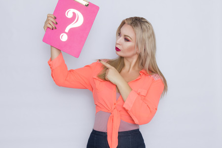 Studio photoshoot of blonde woman holding signboard with question mark
