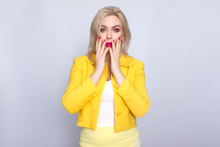 Confident young blonde businesswoman wearing yellow suit standing isolated over white backgroundの写真素材