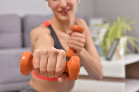 Beautiful young woman in sports clothing practicing sport while spending time at home