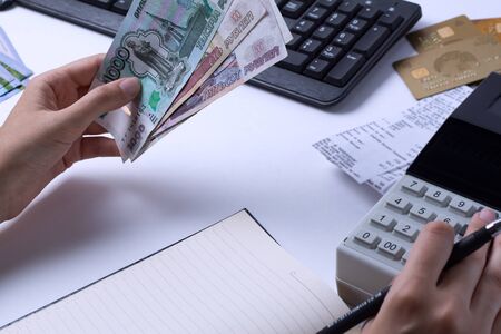 The issue of wages in Russia. Accountant cashier counts the money in rubles and fills the reports and statements. Office worker in the workplace.の写真素材