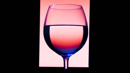 Glass or stemware with alcohol wine,whiskey,gin,beer,rum,vodka,Scotch,cognac,liquor,brandy,absinthe or cocktail on pink background. A glass on the bar in a cafe, restaurant, nightclub or disco.の写真素材