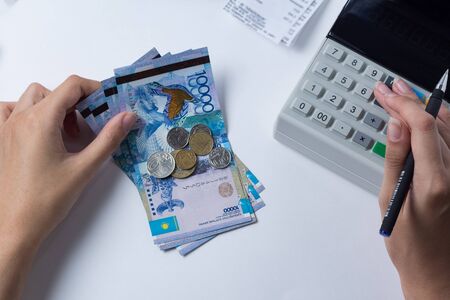Tenge at the cashier accountant in the hands of the workplace in the office. The cashier counts the...