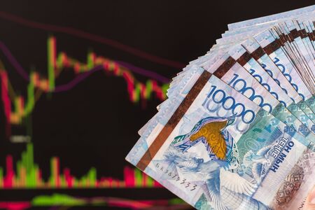 Tenge in Kazakhstan against the background of a laptop with an open chart of the currency market or...