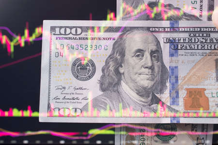 dollars in front of a laptop monitor with a price chart.Forex and trading.A trader trades...