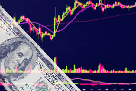 dollars in front of a laptop monitor with a price chart.Forex and trading.A trader trades...