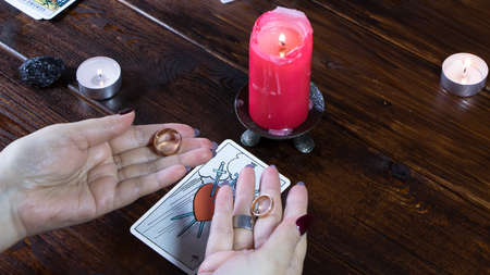 New York, USA-19.05.2020:Candlelight divination on religious holidays and Christmas. A Gypsy fortune teller holds wedding rings by candlelight and guesses at love and relationships.のeditorial素材