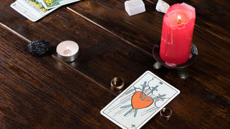 New York, USA-19.05.2020: Wedding rings with fortune-telling cards, lighted candles and magic stones...