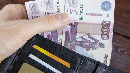 The lot with Russian rubles is pulled out by hand from the wallet with credit cards.Paper banknotes of Russian rubles.Getting a loan from the Bank of Russia. Fall or growth of the ruble exchange rateの写真素材