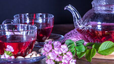 Teapot, mugs of tea, cashew nuts, clove flowers and green medicinal leaves. Tea ceremonies and traditions in Japanese and Zen style. Hot luxury tea with a pleasant smell in a cozy home.Relaxing drinkの写真素材