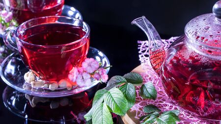 Hot luxury tea with a pleasant smell in a cozy home.Relaxing drink.Teapot, mugs of tea, cashew nuts, clove flowers and green medicinal leaves. Tea ceremonies and traditions in Japanese and Zen styleの写真素材