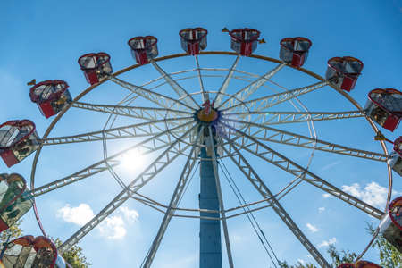 Ferris wheel with cabins in the shape of hearts on a background of blue sky. A romantic walk on the...