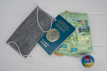 Quarantine in Kazakhstan. Tenge money with medical face masks, a globe, a card and a passport are on the table. The closure of borders and travel in Kazakhstan.の写真素材