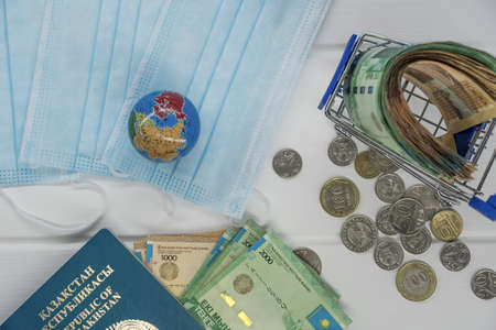 Quarantine in Kazakhstan. Tenge money with medical face masks, a globe, a card and a passport are on...