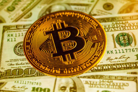 Bitcoin coin against the background of us dollars. A lot of American money dollars and gold bitcoin....