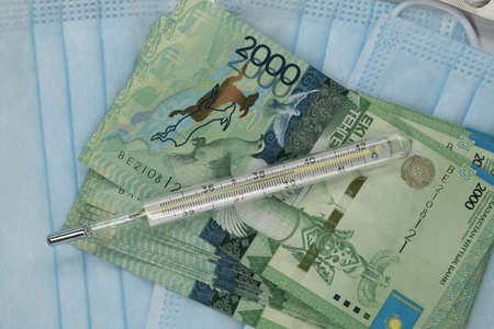 Thermometer, tablet, medical mask and tenge money are on the table. Increase in the price of...