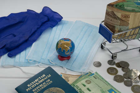 Quarantine in Kazakhstan. Tenge money with medical face masks, a globe, a card and a passport are on the table. The closure of borders and travel in Kazakhstan.の写真素材